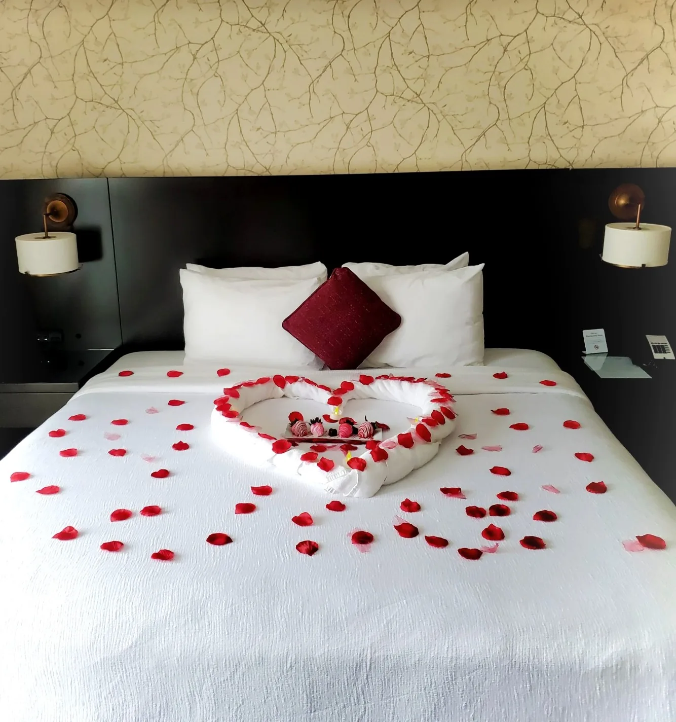 Rose petals arranged in a heart on a guest bed